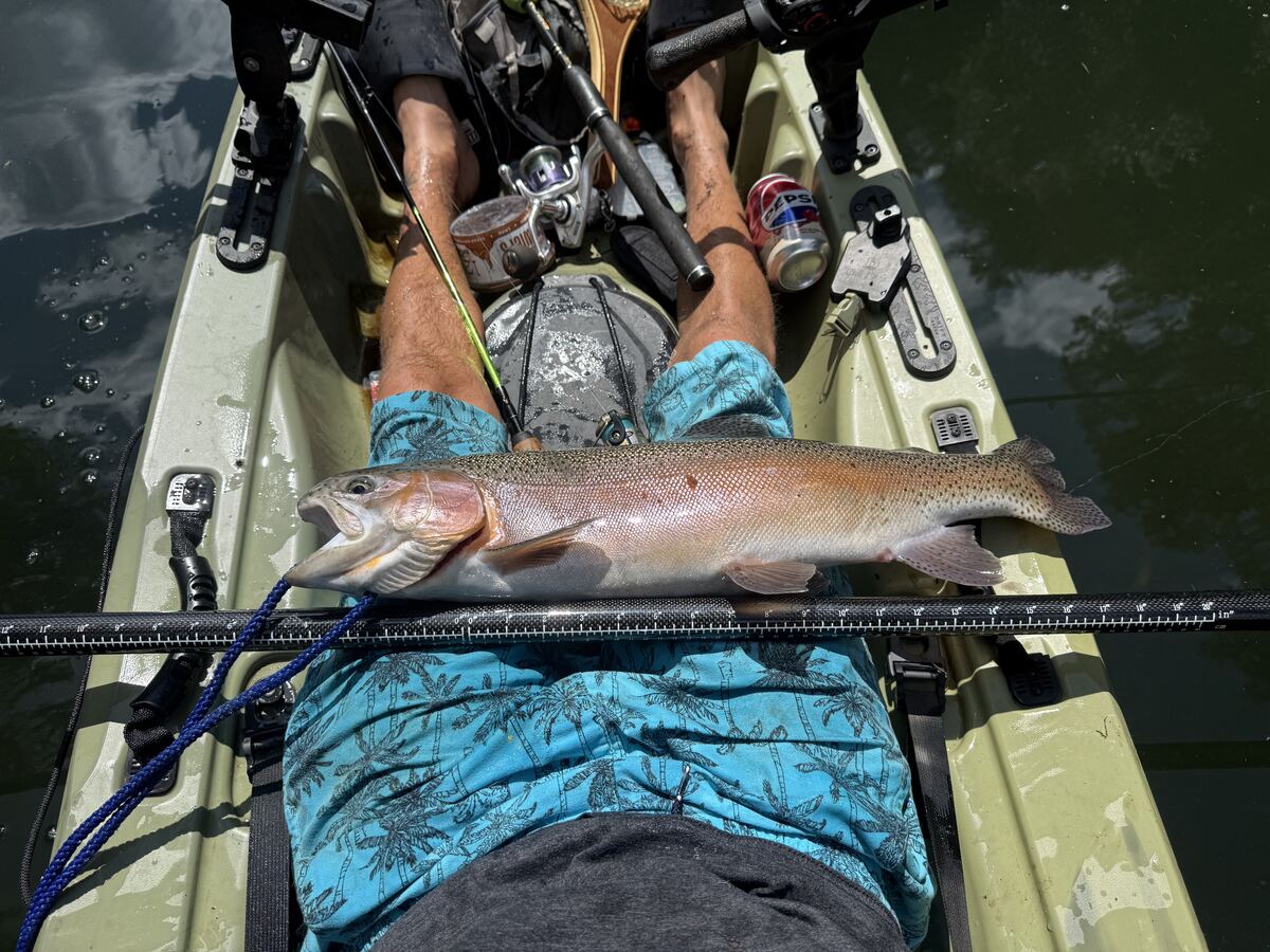 Large trout measured on a tape measure across a kayak